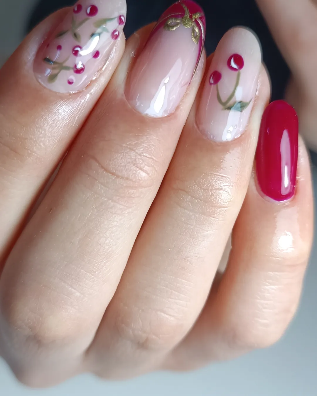 Uñas nude con flores rojas pintadas a mano y una uña roja
